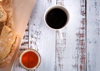 Sandviçler için taze baget sadece fırından fırın tepsisi üzerinde, mutfakta bal yakınındaki ahşap beyaz masada ve içecekler.. 