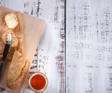 Sandviçler için taze baget sadece fırından fırın tepsisi üzerinde, mutfakta bal yakınındaki ahşap beyaz masada ve içecekler.. 