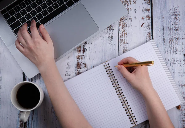 İzolasyon ya da karantina sırasında bir fincan kahveyle bilgisayardan ya da uzaktan öğrenme ve internet üzerinden çalışma. El bir deftere yazar.