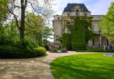 Bina Wroclaw 'daki eski şehir parkında yeşilliklerle kaplı. Polonya. Kukla Tiyatrosu. Yeşil ağaçların ve çiçek açan çiçeklerin etrafında.