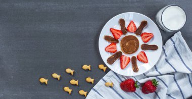 Çocukların kahvaltısı için yaratıcı bir fikir. Güneş şeklinde krepler ve arka planda bir bardak süt. Üst Manzara. Boşluğu kopyala