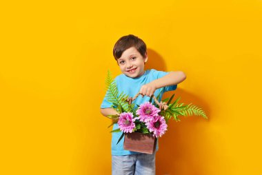 Mutlu güzel çocuk sarı arka planda çiçek buketi tutuyor. Çocuklar doğayı ve mutlu doğayı sever. Modern hayatı.