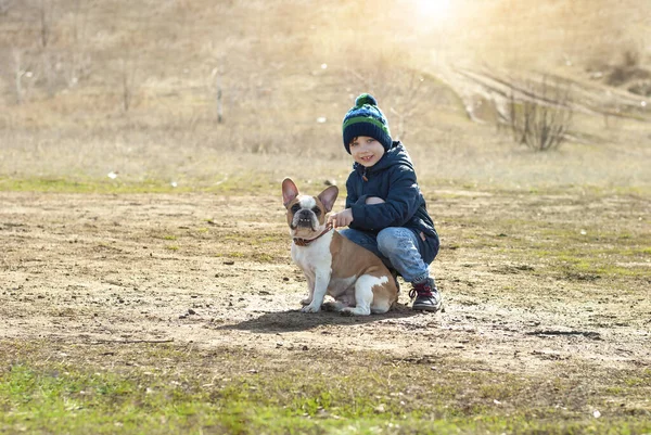 Lifestyle-Porträt eines Jungen beim Spazierengehen und Spielen mit Frech Bulldog an einem sonnigen Frühlingstag im Naturpark Kinder — Stockfoto