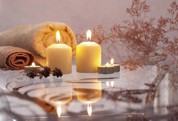 Beautyful burning light yellow creme vanilla candles with bright flame and towels of natural color in the background — Stock Photo, Image