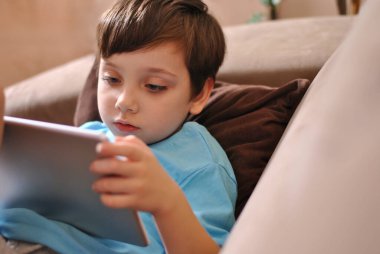 Düşünen küçük çocuk. Çevrimiçi eğitim ve Coronavirus Karantinası. Tablet ve çocuk uzaktan çalışıyor. Salgın çocuklar meşgul ya da evde dinleniyorlar. Ev ödevi hazırlamak için evde kal Boşluğu kopyala