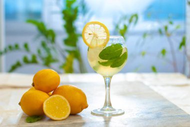 Limonlu buzlu limonata ve limon dilimi ve nane yapraklı bardaklar ve doğal arka plandaki mermer masanın üzerinde. Taze yaz içkisi güzel bir resim. Boşluğu kopyala