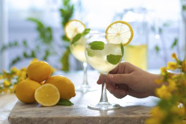 Limonlu buzlu limonata ve limon dilimi ve nane yapraklı bardaklar ve doğal arka plandaki mermer masanın üzerinde. Taze yaz içkisi güzel bir resim. - Evet. Kokteyl bardağıyla.