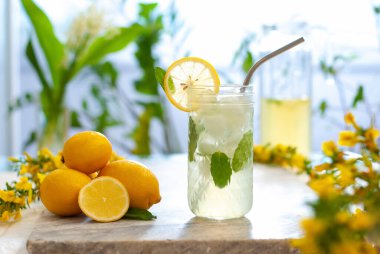 Limonlu buzlu limonata ve limon dilimi ve nane yapraklı bardaklar ve doğal arka plandaki mermer masanın üzerinde. Taze yaz içkisi güzel bir resim. Boşluğu kopyala