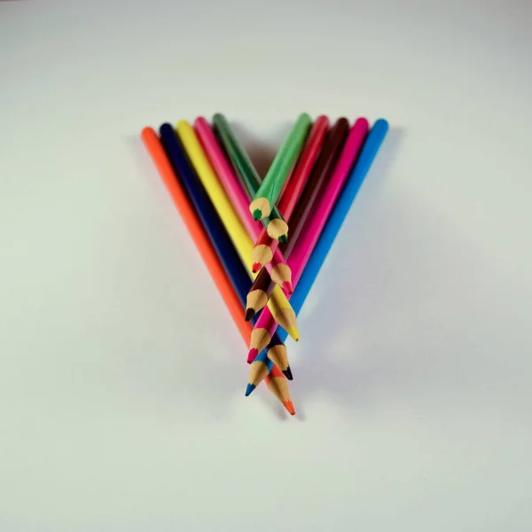 Beyaz arkaplanda farklı renkte tahta kalemler.