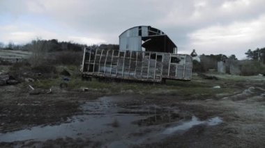 Hasarlı bir at arabası ve Kuzey İrlanda 'da çim ve ağaçlarla kaplı bir arazide terk edilmiş bir barınak. - geniş açı