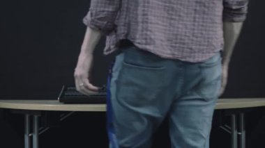 Profesyonel biri aydınlatma masasına doğru yürür ve kaydırıcıları ayarlar.