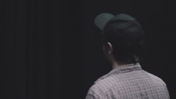一个戴着帽子和衬衫的男人的背影揭开了黑色的帷幕 揭示了后面的白墙 关门射击 — 图库视频影像