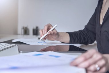 Bir iş kadını pazarlama istatistiklerine danışır ve tabletiyle şirketin çevrimiçi büyümesini analiz eder.