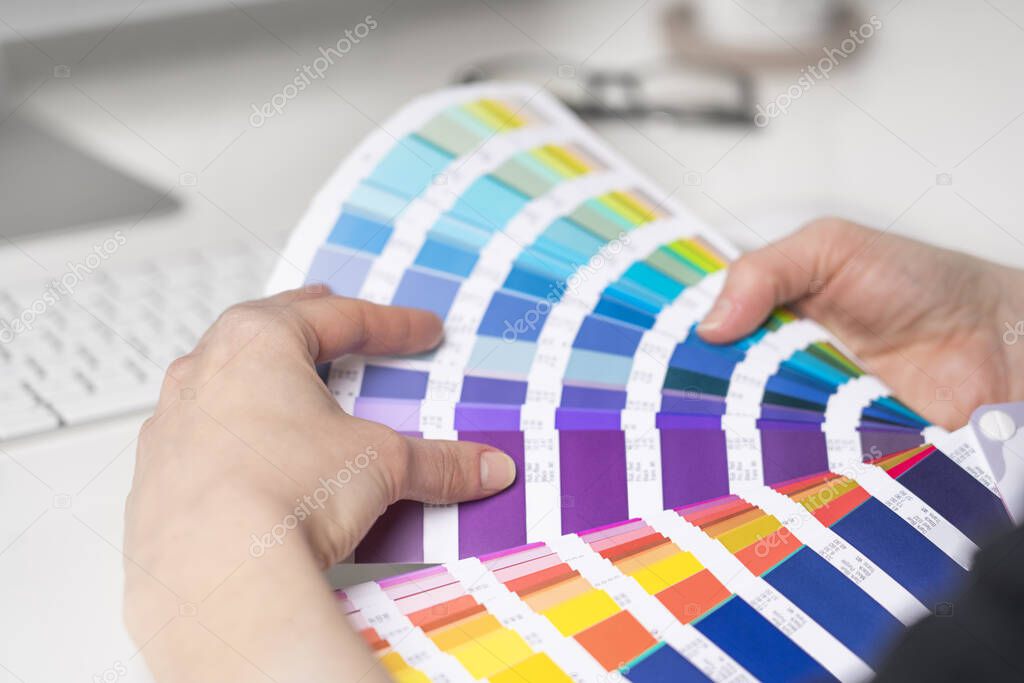 Graphic designer chooses colors from palette guide for painting and printing a new creative business work. 