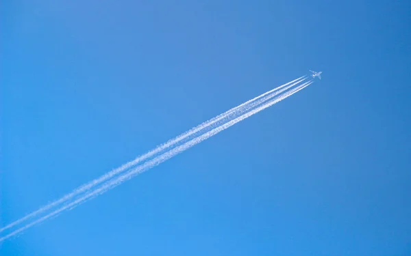 Grande aereo che vola attraverso il cielo blu con tracce di vapore — Foto Stock