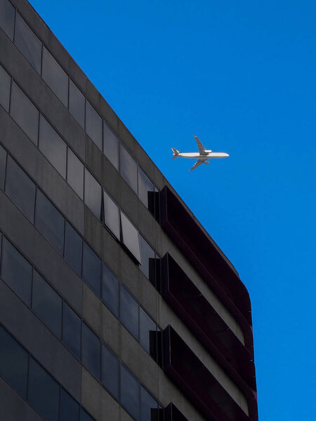 AUSTRALIA, MELBOURNE - January 07, 2015: Comercial airplane flying over office building
