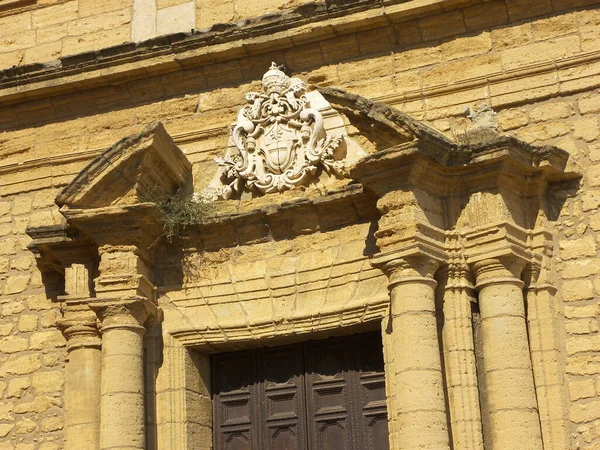 Visiting Agrigento it is possible to see San Pietro church. The building is made by brown stone bricks. The church is located in front of a small square. The entrance door has a square shape and is enriched by some columns. A glass window is located