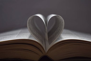 Yapraklarıyla kalp oluşturan incili gri bir arka planda izole edilmiş.