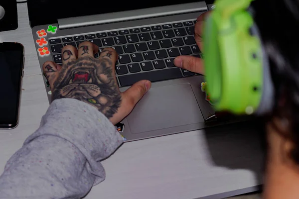 タトゥーのある男がノートパソコンのキーボードで — ストック写真