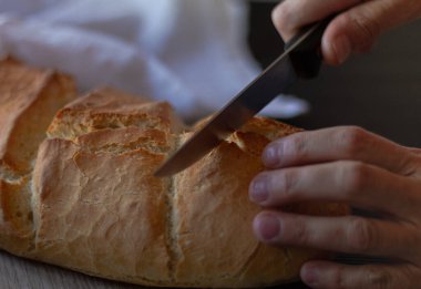 Sağlıklı bir Akdeniz yemeği için taze pişmiş ve kızarmış ekmek dilimliyorum.