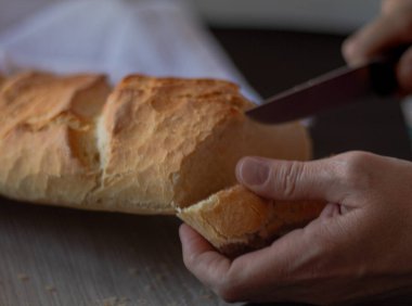 Sağlıklı bir Akdeniz yemeği için taze pişmiş ve kızarmış ekmek dilimliyorum.
