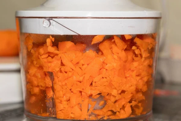 chopping carrots with an electric food processor to make a homemade cake