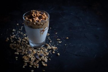 Bir bardak sütlü, kremalı kahve, müsli gevreği ve çikolata parçacıklı.