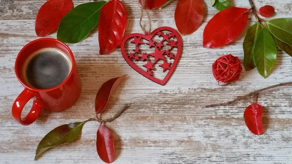 Fincan kahve, kırmızı kalp ve ahşap arka plan üzerinde sonbahar yaprakları 