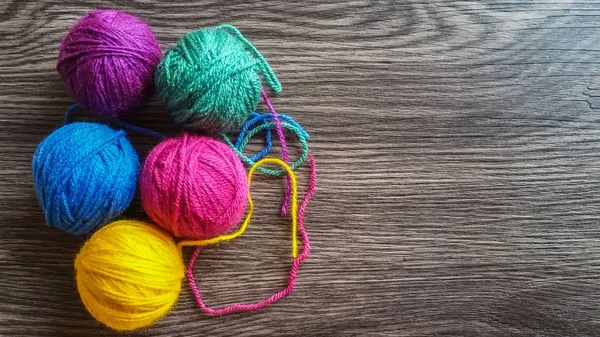 Multicolored yarn on dark wooden background — Stock Photo, Image