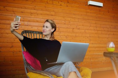 Genç freelancer net-kitap yolu ile ağ çalışması sırasında cep telefonu kamera ile fotoğraf yapıyor. 