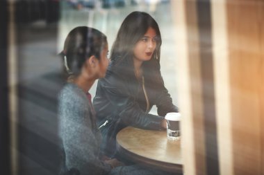 Young women having conversation during work break meeting in cafe. Two female are resting in bar with take away coffee. 