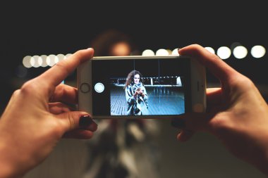 Ekranda fotoğraf kamera modu ile cep telefonu tutan kadın elleri yakından görüntü.