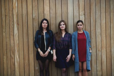 Serin moda giysiler giymiş güzel kadınlar kamera bakıyor, açık havada ayakta iken. 