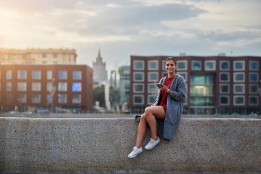 Güzel kadın turist elinde cep telefonu ile muhteşem bahar günü onu hafta sonu boyunca yurtdışında keyif alıyor.