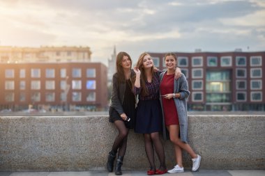 Üç kadın en iyi arkadaş poz verirken, St. Petersburg şehrinde yürüyüş turları sırasında nehir iskelesi yakınında duruyorlar..