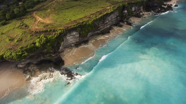 Kumlu kıyı şeridi üzerinde kayalık ile inanılmaz bir doğa sahne uçan drone hava fotoğrafı. Bali yaz sezonunda sörf için dalgalar ile güzel deniz suyu.