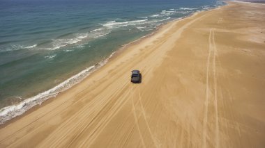 Gezginlerin drone havadan fotoğraf Asya'ya yolculuk sırasında mavi su ile sakin denize yakın bir plajda bir pikap makinesi üzerinde sürme