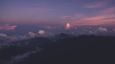 Dağların silueti üzerinde pembe gün batımı ile inanılmaz güzel renkli gökyüzü uçak kokpitten hava fotoğrafı. 