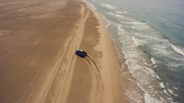 Güzel dalgalar ile denize yakın kumlu bir plajda bir binicilik pikap makinesi uçan drone hava fotoğrafı.