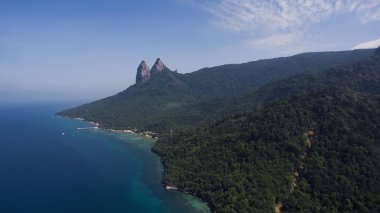 Mavi gökyüzüne karşı kayalık kayalar ile yeşil ada ile güzel bir doğa manzara uçan drone hava fotoğrafı. 