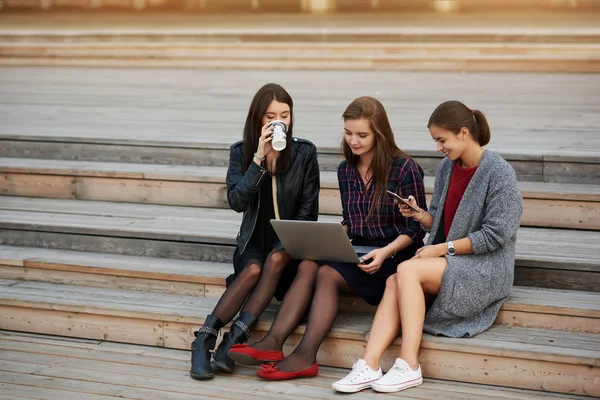 女性看电影在互联网上通过便携式网络书，在他们的朋友阅读文本消息细胞电话时 — 图库照片