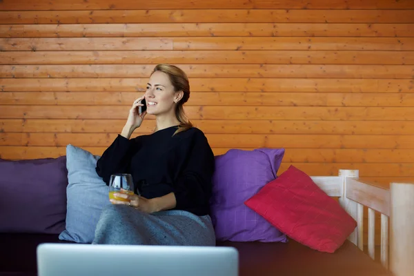 Vakker kvinnelig advokat snakker i smarttelefon om sin seier i søksmålet, mens han sitter hjemme med glasjuice. – stockfoto