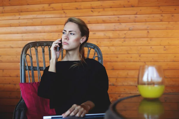 Empreendedora mulher séria está ligando para o cliente no telefone celular, enquanto está esperando por ele no café . — Fotografia de Stock