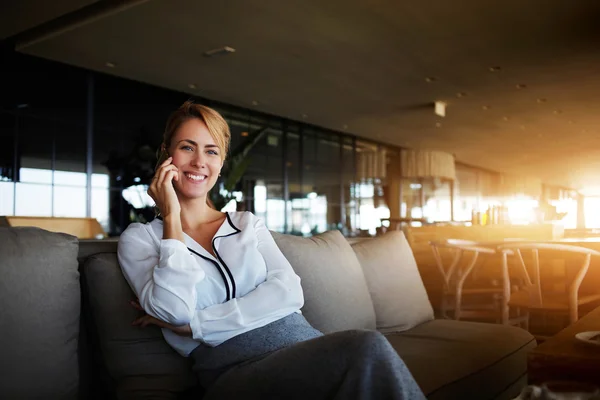 Mujer alegre con hermosa sonrisa teniendo una agradable conversación telefónica móvil durante el tiempo de recreación en la cafetería — Foto de Stock