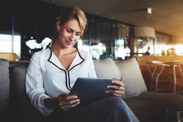 Финансистка читает финансовые новости в Интернете через сенсорную панель во время рабочего перерыва в современном кафе
