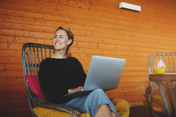 Mulher feliz está sorrindo para alguém, enquanto está sentado com computador portátil no interior da cafetaria hipster . — Fotografia de Stock