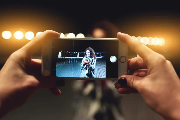 Gros plan image d'une femme fait la photo d'une jeune fille hipster avec téléphone intelligent appareil photo numérique pendant leur marche à l'extérieur dans la soirée . — Photo