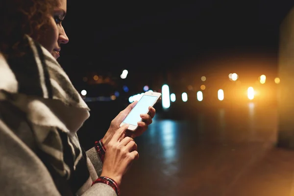Женщина-туристка ищет способ навигации по сотовому телефону, пока стоит на улице ночью . — стоковое фото