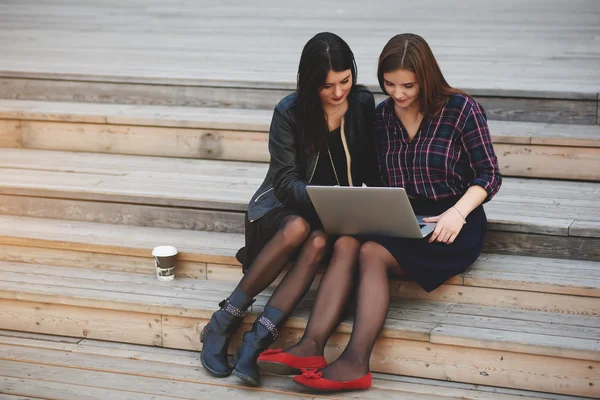 Las mujeres están viendo vídeo en la red social a través de la red portátil, mientras se relaja al aire libre . — Foto de Stock