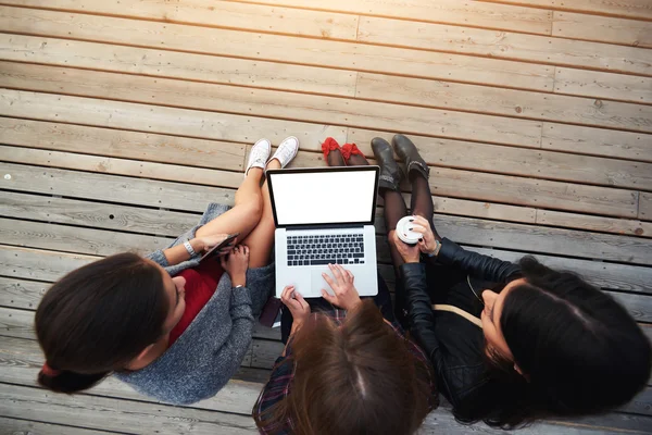 Tető kilátás-ból egy három asszonyok hallgató van keres-ra pókháló oldal keresztül laptop számítógép érdekes hely részére pihenés. — Stock Fotó